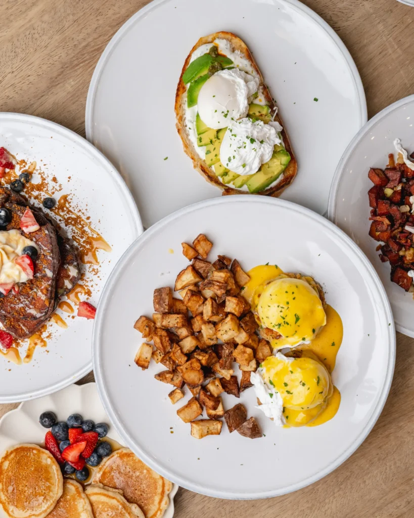 brunch spread with eggs benedict, avocado toast, pancakes, and breakfast potatoes