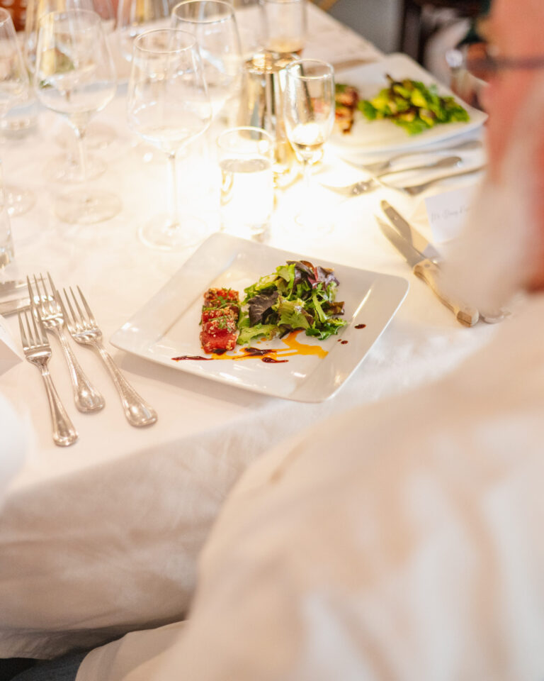 Close-up of plated salad with greens and red garnish at table.