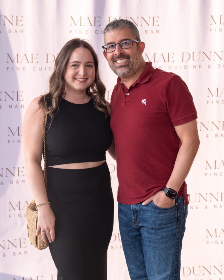 Smiling couple posing together in front of restaurant backdrop.